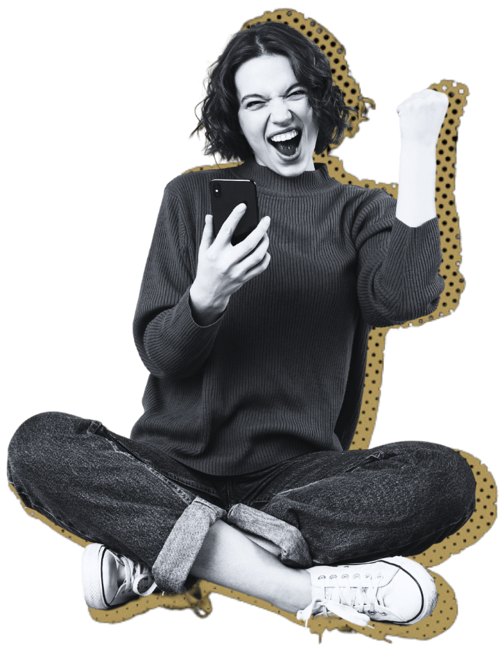 Person sitting cross-legged, looking at a smartphone with an excited expression, raising a fist in celebration.